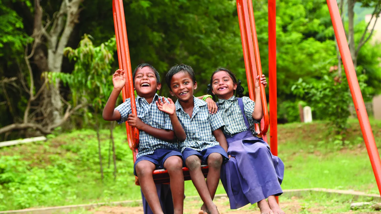 Children smiling together on a swing in India